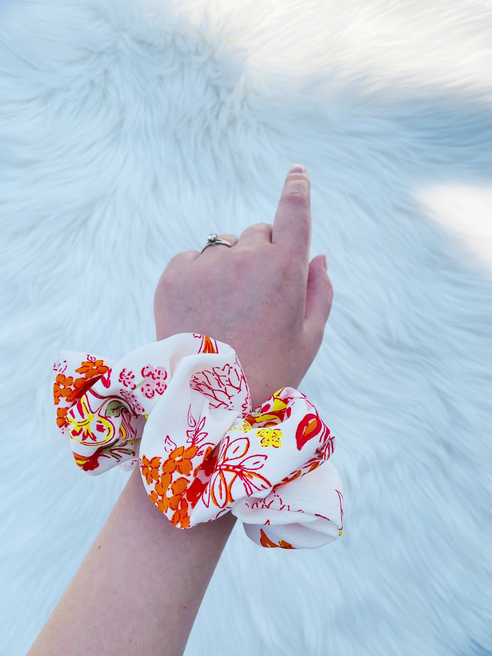 POPPY|EMI AND CO| White and orange floral scrunchie on wrist 