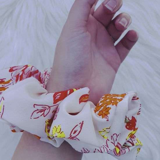 POPPY|EMI AND CO| White and orange floral scrunchie on wrist 