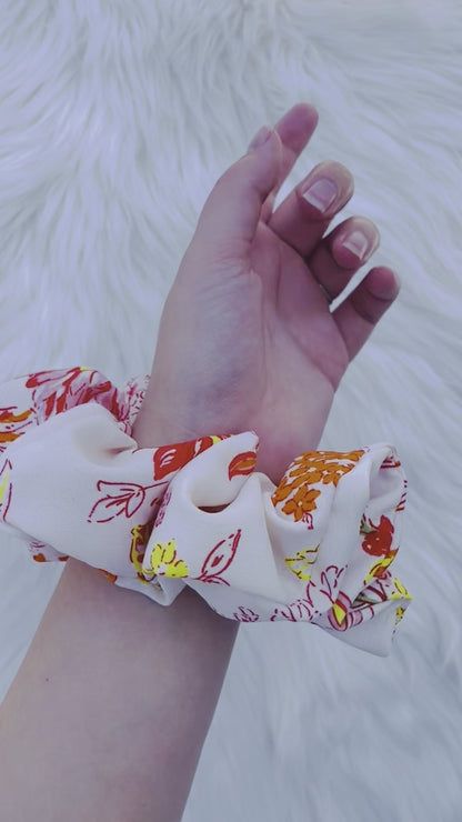 POPPY|EMI AND CO| White and orange floral scrunchie on wrist 